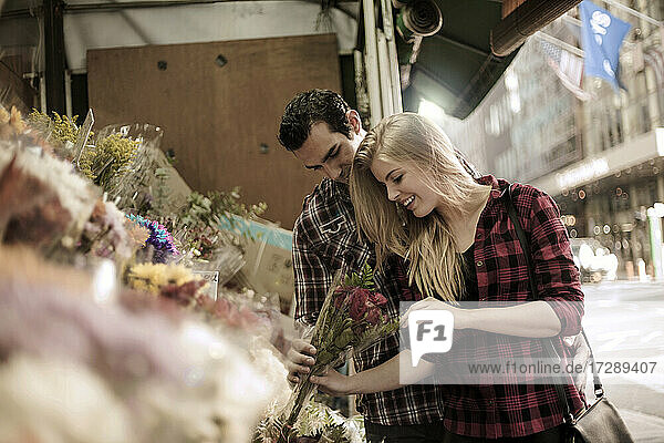 Schöne Frau betrachtet Blumen von ihrem Freund im Geschäft