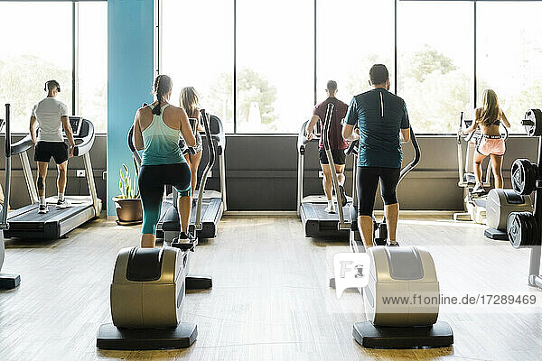 Männer und Frauen an Trainingsgeräten im Fitnessstudio