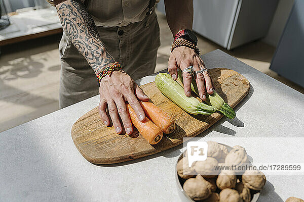 Mann stehend neben Gemüse und Schneidebrett auf Kücheninsel zu Hause