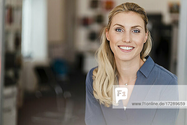 Schöne lächelnde Geschäftsfrau mit blondem Haar im Büro