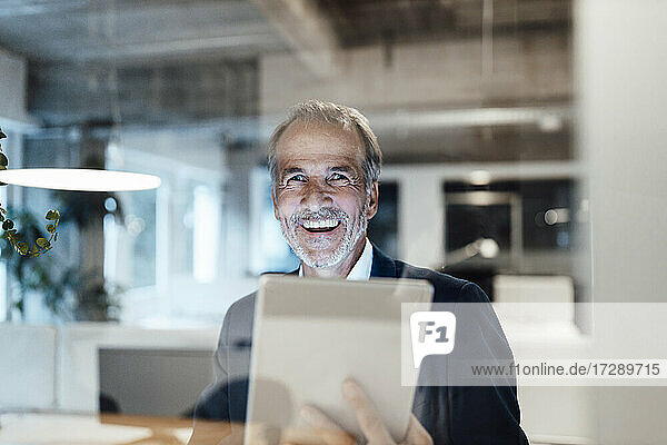 Cheerful businessman with digital tablet at office