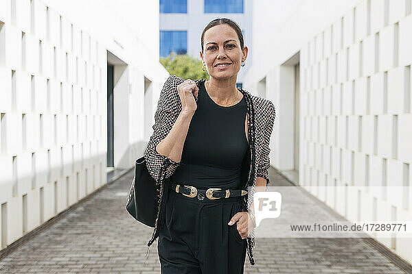 Mature female entrepreneur with purse standing on footpath