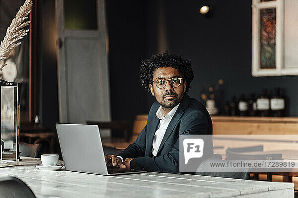 Reifer Geschäftsmann  der einen Laptop benutzt  während er in einem Café sitzt