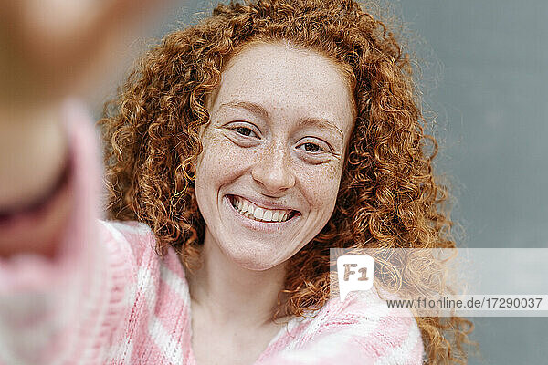 Fröhliche rothaarige Frau mit lockigem Haar lächelnd