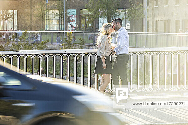 Romantisches Paar  das sich küsst  während es am Geländer steht