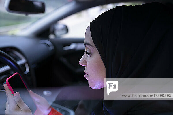 Frau benutzt Smartphone  während sie im Auto sitzt