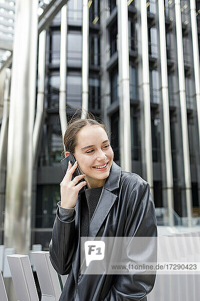 Lächelnde Unternehmerin  die in der Stadt mit einem Mobiltelefon spricht