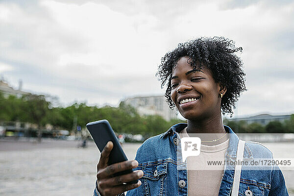 Smiling woman using mobile phone in city