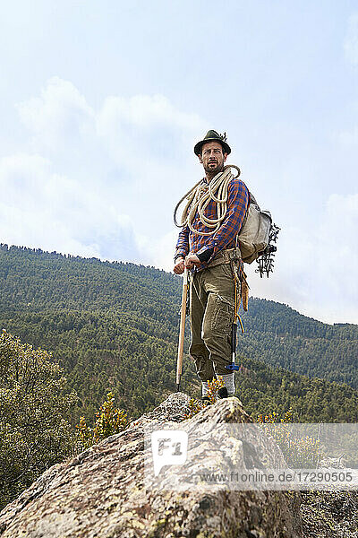Male mountaineer with backpack and equipment standing on mountain