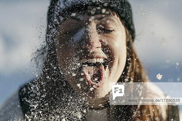 Mid adult woman sticking out tongue while playing during snowing