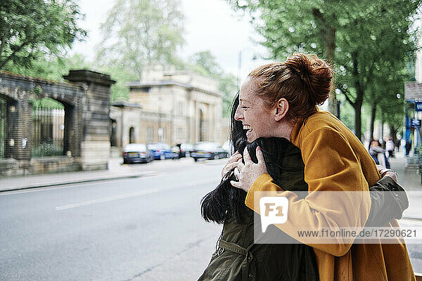 Glückliche Freundinnen umarmen sich auf der Straße