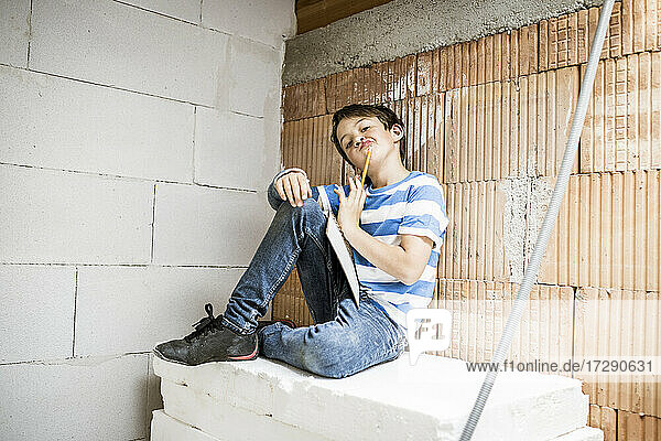 Nachdenklicher Junge  der beim Umbau eines Hauses auf einem Block sitzt