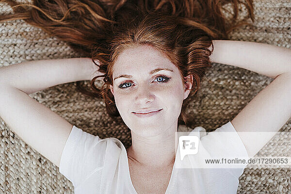 Smiling beautiful woman lying on floor at home