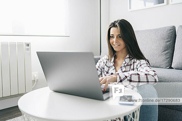 Junge schöne Frau benutzt Laptop zu Hause
