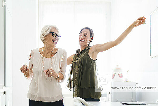 Glückliche Frau tanzt mit Großmutter in der Küche zu Hause