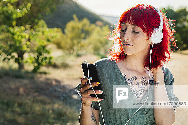 Hipster-Frau mit roten Haaren  die ein Smartphone an einem sonnigen Tag benutzt