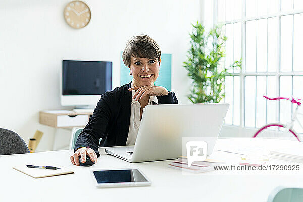 Geschäftsfrau sitzt mit Laptop am Schreibtisch im Büro