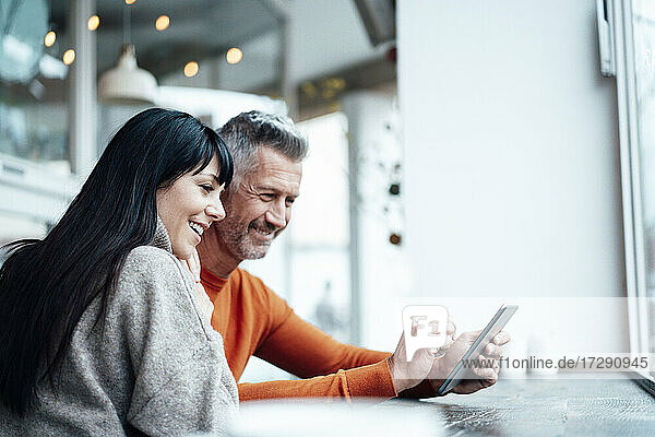 Lächelndes reifes Paar benutzt Smartphone im Café