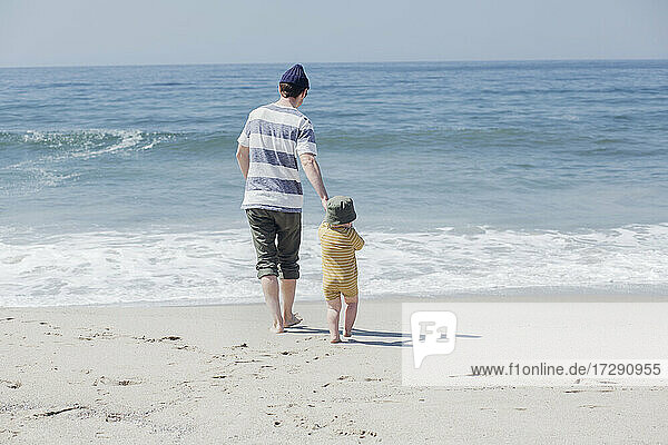 Vater mit Sohn geht am Strand zum Wasser