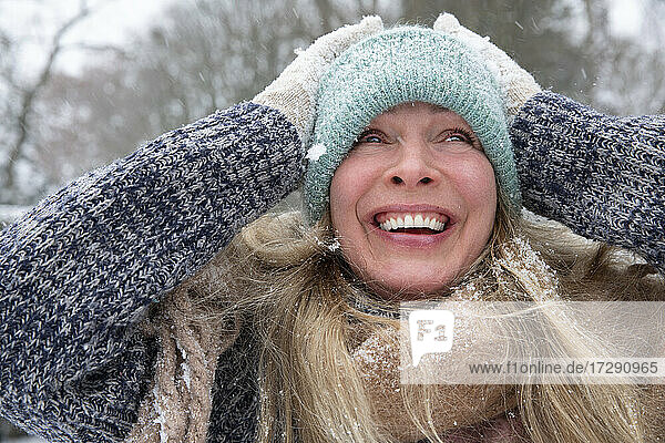 Ältere Frau mit Strickmütze  die lachend wegschaut  im Winter