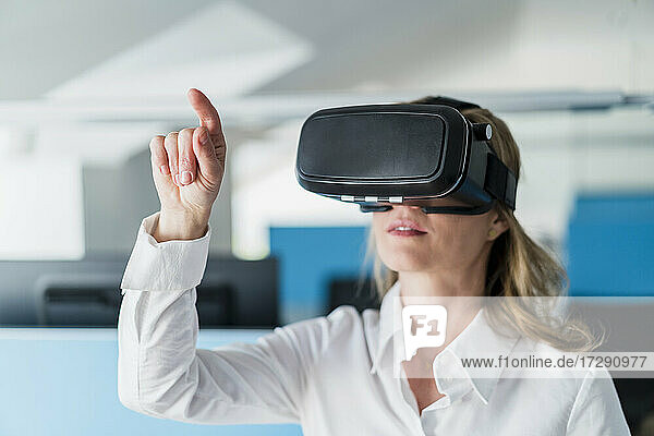 Geschäftsfrau gestikuliert bei der Verwendung eines Virtual-Reality-Headsets im Büro