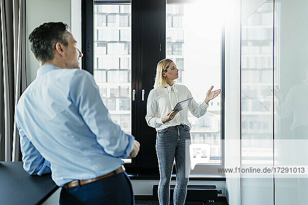 Eine Frau erklärt einem Geschäftsmann ihre Strategie  während sie im Büro diskutiert