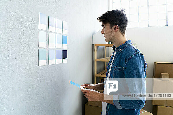 Male professional looking at blue cards on wall in warehouse