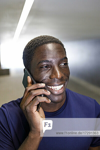 Lächelnder Mann  der in der U-Bahn mit einem Mobiltelefon spricht