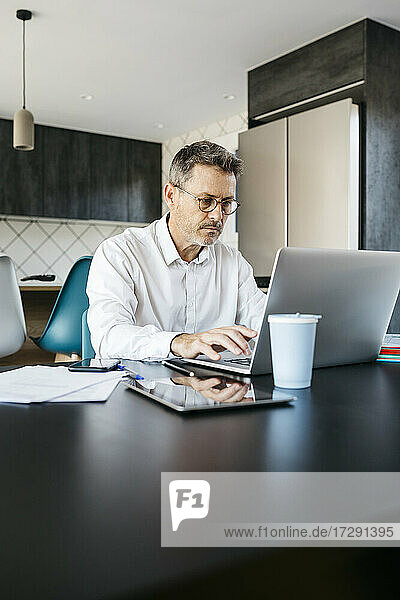 Geschäftsmann arbeitet am Laptop in der heimischen Küche im Home Office