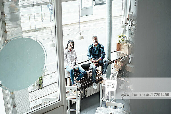 Weibliche und männliche Unternehmer sitzen am Fenster eines Cafés