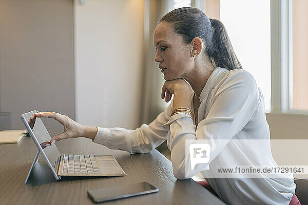 Reife Geschäftsfrau  die ein digitales Tablet bei der Arbeit im Büro benutzt