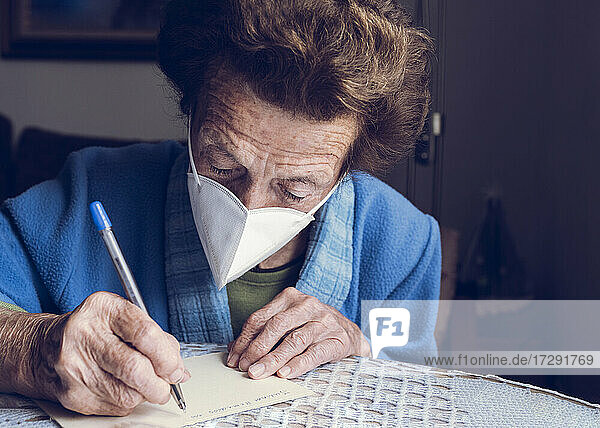 Ältere Frau schreibt zu Hause auf Papier
