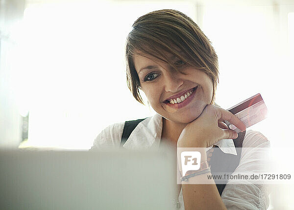 Lächelnde Geschäftsfrau mit Kreditkarte und Laptop