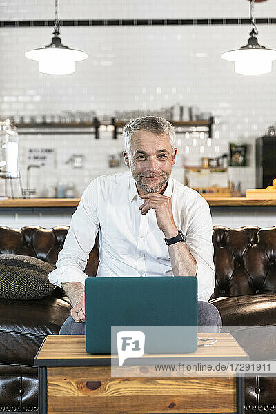 Smiling male entrepreneur sitting on sofa at office