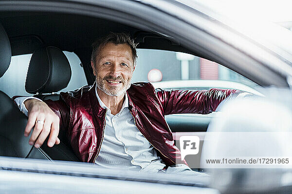 Älterer Mann lächelnd im Auto sitzend