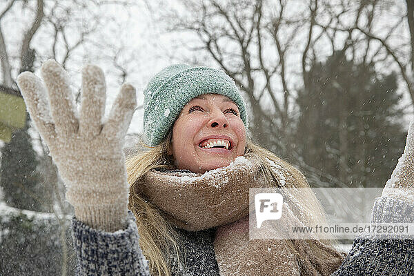 Fröhliche blonde Frau beim Schneewerfen und Spielen im Winter