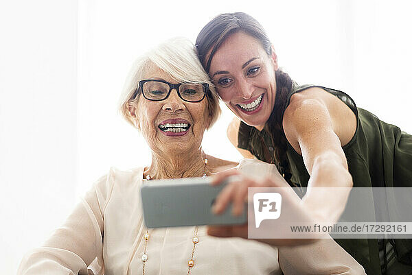 Glückliche Frau nimmt Selfie mit Großmutter durch Handy zu Hause