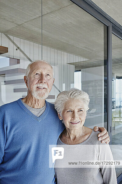 Älteres Paar steht zusammen vor einer Glaswand