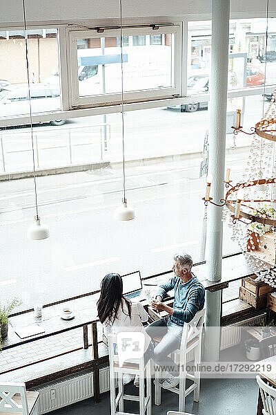 Reife männliche und weibliche Besitzer  die im Café sitzen und arbeiten