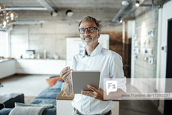 Senior businessman standing with digital tablet at office