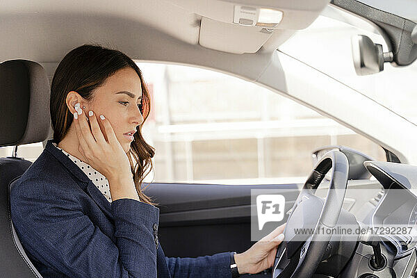 Unternehmerin spricht beim Autofahren durch In-Ear-Kopfhörer