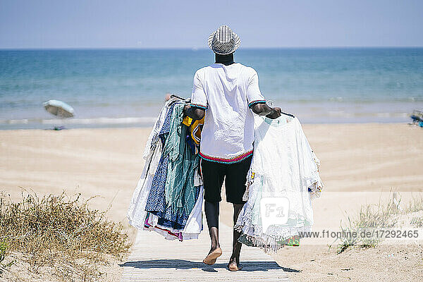 Vendor with dresses for sale walking on boardwalk at beach