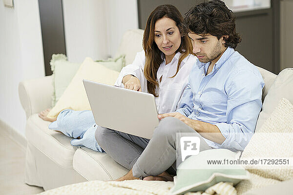 Couple talking while watching on laptop at new home