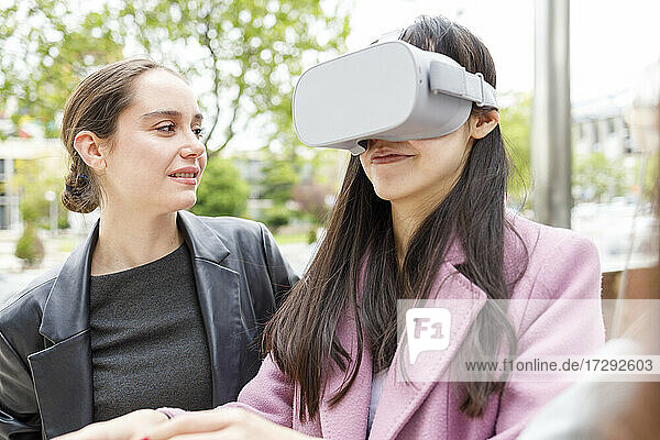 Geschäftsfrau  die einen Kollegen mit einem Virtual-Reality-Headset betrachtet