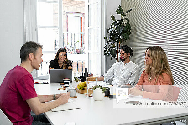 Lächelnde männliche und weibliche Fachkräfte diskutieren während eines Treffens im Coworking-Büro