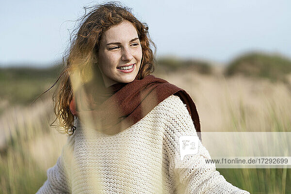 Smiling woman contemplating while standing in dunes during vacations