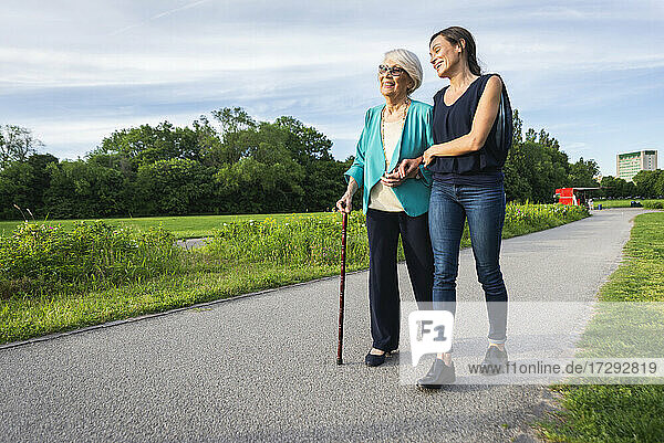 Lächelnde ältere Frau mit halbwüchsiger Frau auf dem Fußweg im Park