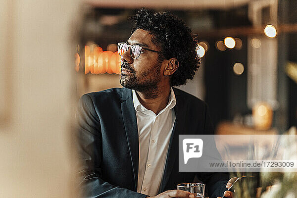 Male entrepreneur wearing eyeglasses in cafe looking away