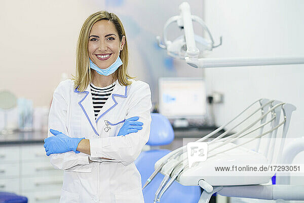 Lächelnde Zahnärztin mit verschränkten Armen in einer medizinischen Klinik