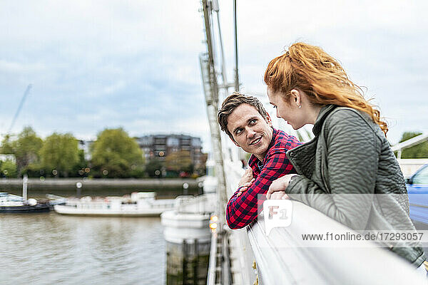 Mann sieht seine Freundin an  während er sich auf einem Brückengeländer abstützt
